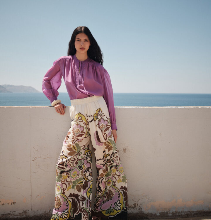 Model trägt eine flieder-farbige Bluse und eine bunte Hose der Marke Devotion.