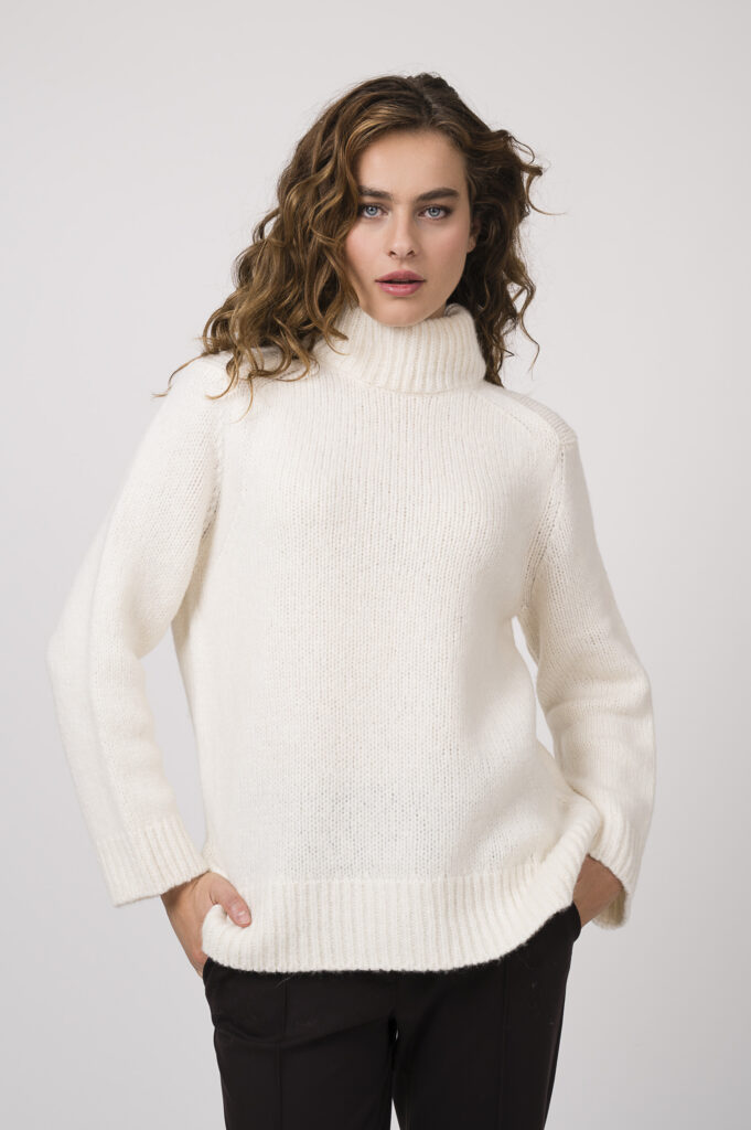 Model zeigt einen natur-farbigen Stehkragenpullover der Marke Dorothee Schumacher, eine braue Stoffhose der Marke Dorothee Schumacher