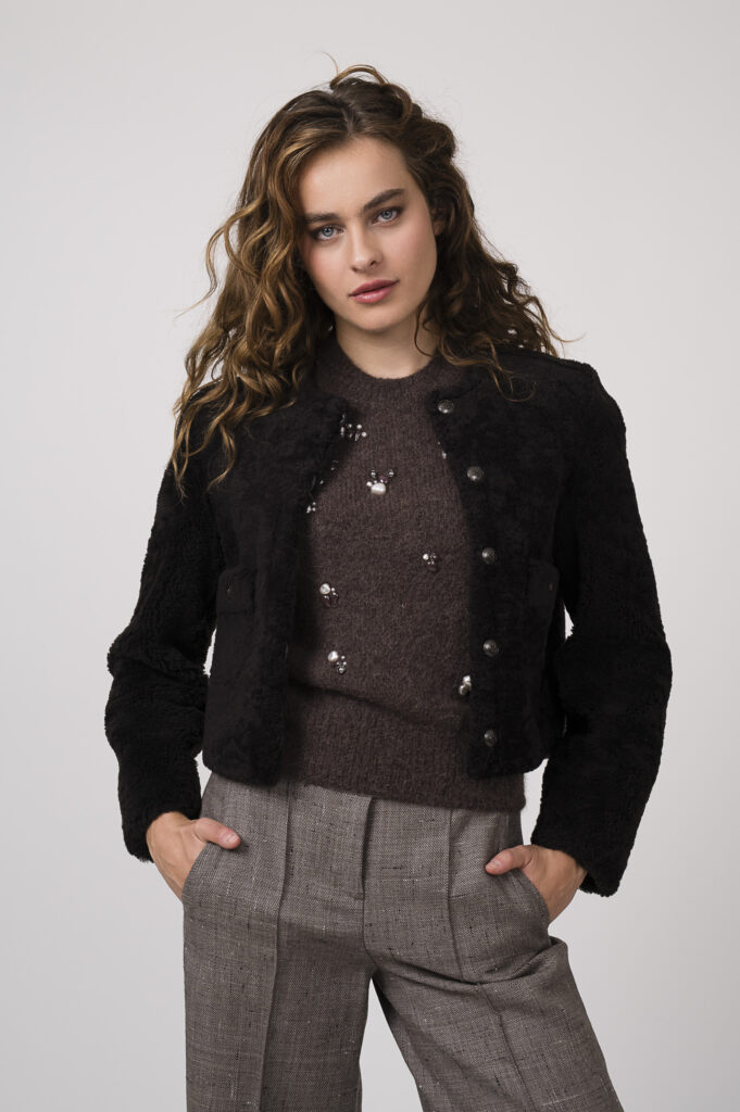 Model zeigt einen braunen Pullover mit Perlendekor der Marke Dorothee Schumacher, eine braue Stoffhose der Marke Dorothee Schumacher und eine Wendejacke der Marke Dorothee Schumacher.