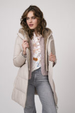 Model zeigt eine beige Daunenjacke der Marke Duno, eine rosa Strickweste der Marke Michele & Hoven, eine gemusterte Bluse der Marke Herzens’Angelegenheit und eine mittelgraue Jeans der Marke 7 for all mankind.