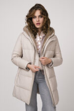 Model zeigt eine beige Daunenjacke der Marke Duno, eine rosa Strickweste der Marke Michele & Hoven, eine gemusterte Bluse der Marke Herzens’Angelegenheit und eine mittelgraue Jeans der Marke 7 for all mankind.