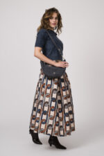 Model zeigt einen taubenblauen Kurzarmpullover mit Kragen der Marke Lisa Yang, eine Tasche der Marke Aigner und einen Rock der Marke Lunatica.