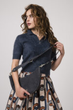 Model zeigt einen taubenblauen Kurzarmpullover mit Kragen der Marke Lisa Yang, eine Tasche der Marke Aigner und einen Rock der Marke Lunatica.