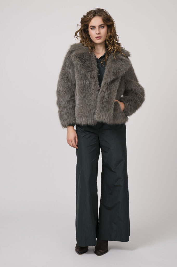 Model zeigt eine hellgraue Fake Fur Jacke Betta Corradi und eine Blazerjacke und Hose in smaragd-grün der Marke Susanne Bommer.