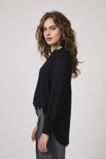 Model zeigt eine schwarze Bluse mit Strass-Dekor am Kragen der Marke Janice & Jo, eine mittelgraue Stoffhose der Marke Cambio und einen Gürtel der Marke Dorothee Schumacher.