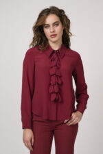 Model zeigt ein Outfit der Marke Luisa Cerano bestehend aus einer bordeaux-roten Bluse mit Vollant und einer bordeaux-roten Hose.