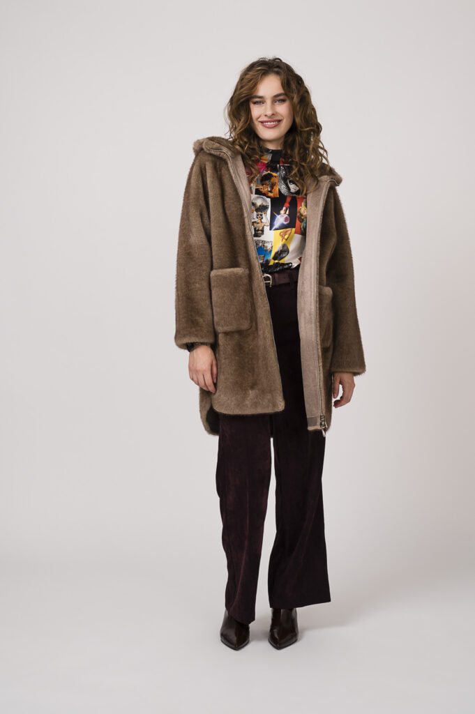 Model zeigt eine bunt gemusterte Bluse der Marke unbreak.it, eine bordeaux-farbige Kordhose der Marke Cambio, einen Gürtel der Marke Aigner und ein Fake Fur Mantel in taupe der Marke Betta Corradi.