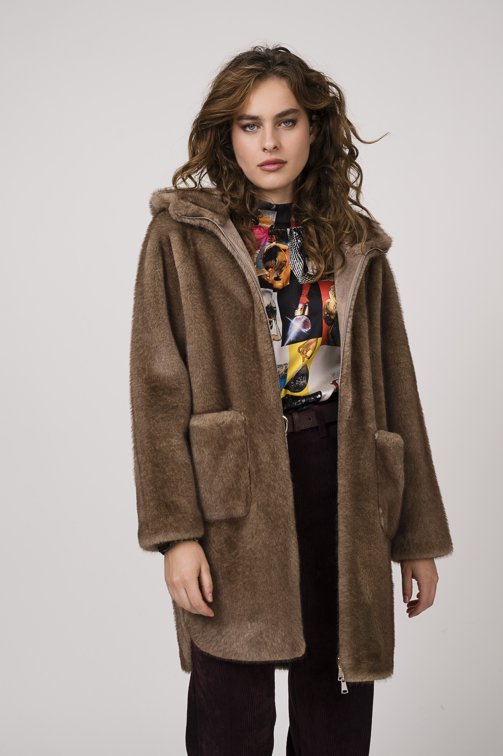 Model zeigt eine bunt gemusterte Bluse der Marke unbreak.it, eine bordeaux-farbige Kordhose der Marke Cambio, einen Gürtel der Marke Aigner und ein Fake Fur Mantel in taupe der Marke Betta Corradi.