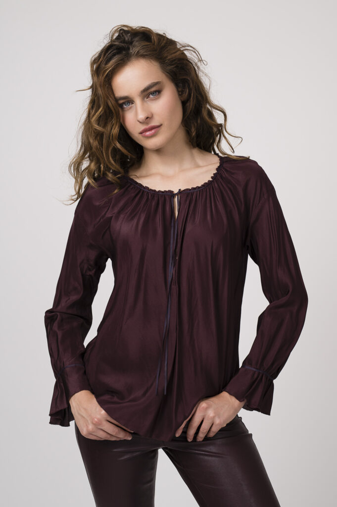 Model zeigt ein Outfit der Marke Susanne Bommer - bestehend aus einem langärmligen bordeaux-roten Seidenshirt, einer bordeaux-roten Hose der Marke Cambio.