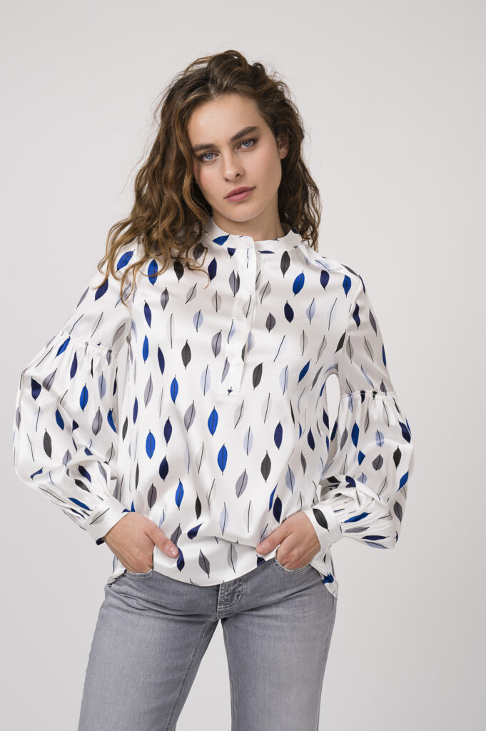 Model zeigt eine gemusterte Bluse der Marke Herzens'Angelgenheit, eine Jeans der Marke Cambio.