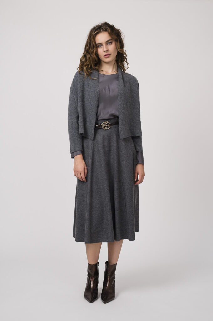 Model zeigt ein graues Outfit der Marke Susanne Bommer bestehend aus einem Seidentop, einer Weste und einem Rock kombiniert mit einem Gürtel der Marke Dorothee Schumacher.