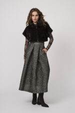 Model zeigt ein halbtransparentes Oberteil der Marke Grace, einen Rock der Marke Lunatica in smaragd und ein ärmelloses Fake Fur Gilet von Betta Corradi.