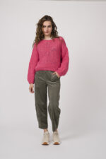 Model zeigt einen pinken Strickpullover der Marke Michele & Hoven, eine beige gemusterte Bluse der Marke Grace, eine olivgrüne Hose der Marke Cambio und Sneaker der Marke Voile Blanche.