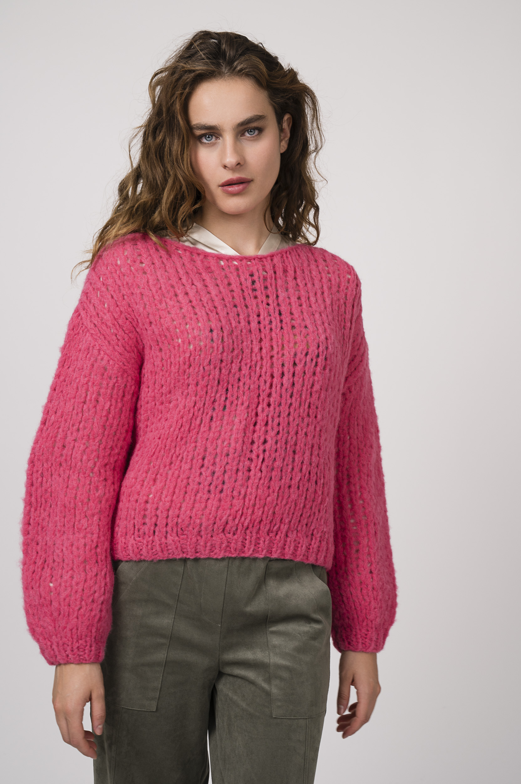 Model zeigt einen pinken Strickpullover der Marke Michele & Hoven, eine beige gemusterte Bluse der Marke Grace und eine olivgrüne Hose der Marke Cambio.