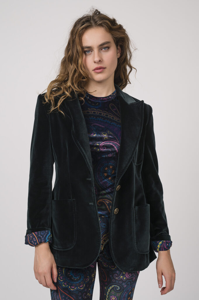 Model zeigt ein samtiges Outfit der Marke ETRO, bestehend aus einer petrol-farbig gemusterten Hose und einem Shirt sowie einem smaragd-grünen Blazer.