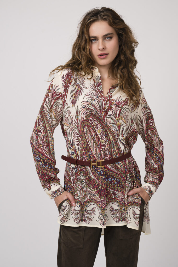 Model zeigt eine beige, bordeaux-farbige Bluse der Marke ETRO, einen Gürtel der Marke Hemisphere und eine schoko-braune Hose der Marke Cambio.