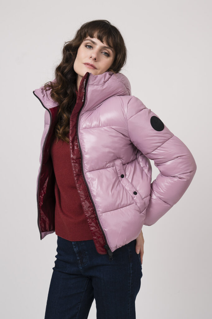 Model zeigt eine Steppjacke der Marke Save the duck in rosa, einen Pullover mit Stehkragen der Marke Luisa Cerano in bordeaux, dazu eine boot cut Jeans der Marke 7 for all mankind dark blue denim