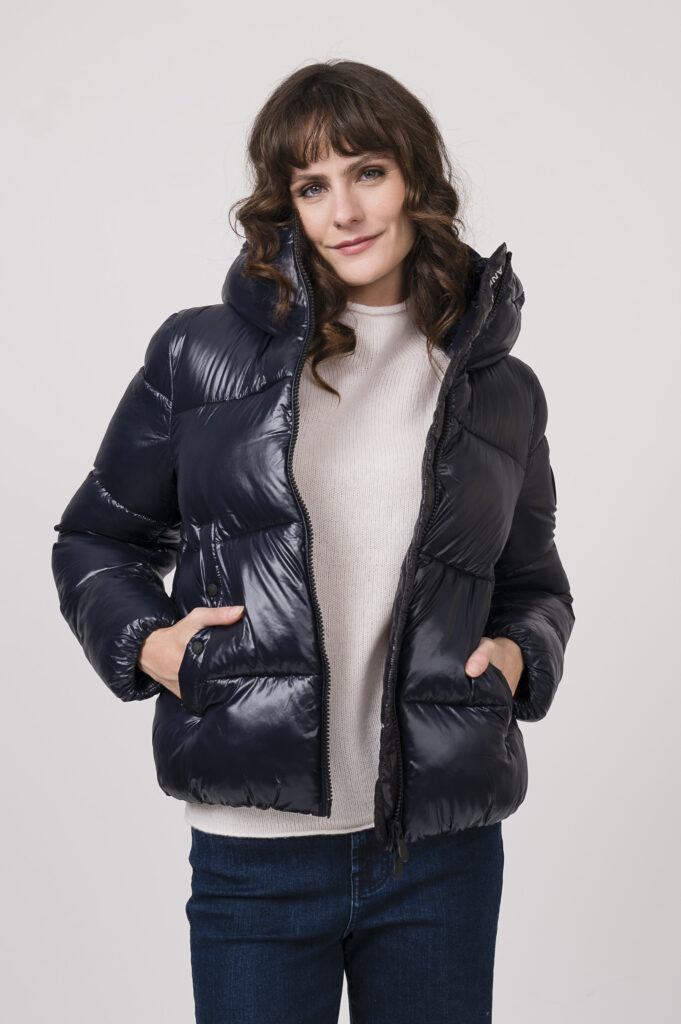 Model zeigt eine Steppjacke der Marke Save the duck in marine, einen Stehkragenpullover der Marke Allude in stein, dazu eine boot cut Jeans der Marke 7 for all mankind in dark blue denim