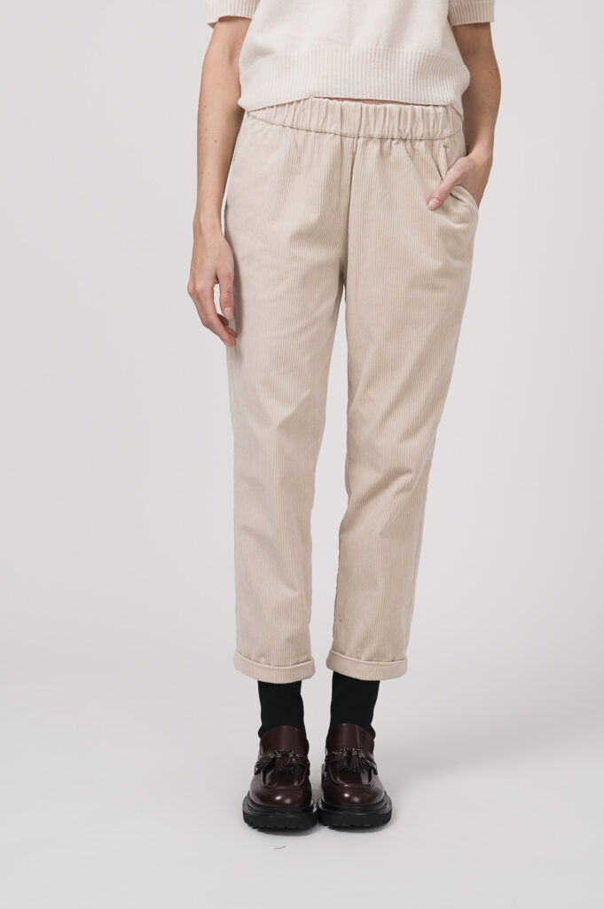 Model zeigt eine Kurzarmpullover der Marke Allude in natur aus cashmere, dazu eine Cordhose der Marke Lis Lareida in sand