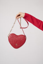 Model zeigt eine herzförmige rote Tasche der Marke Aigner.