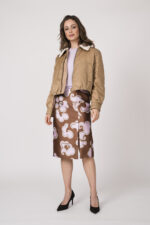 Model trägt eine beige Daunen-Wendejacke der Marke Luisa Cerano, eine flieder-farbigen Kurzarmpullover und einen beige rosa gemusterten Bleistiftrock der Marke Dorothee Schumacher.