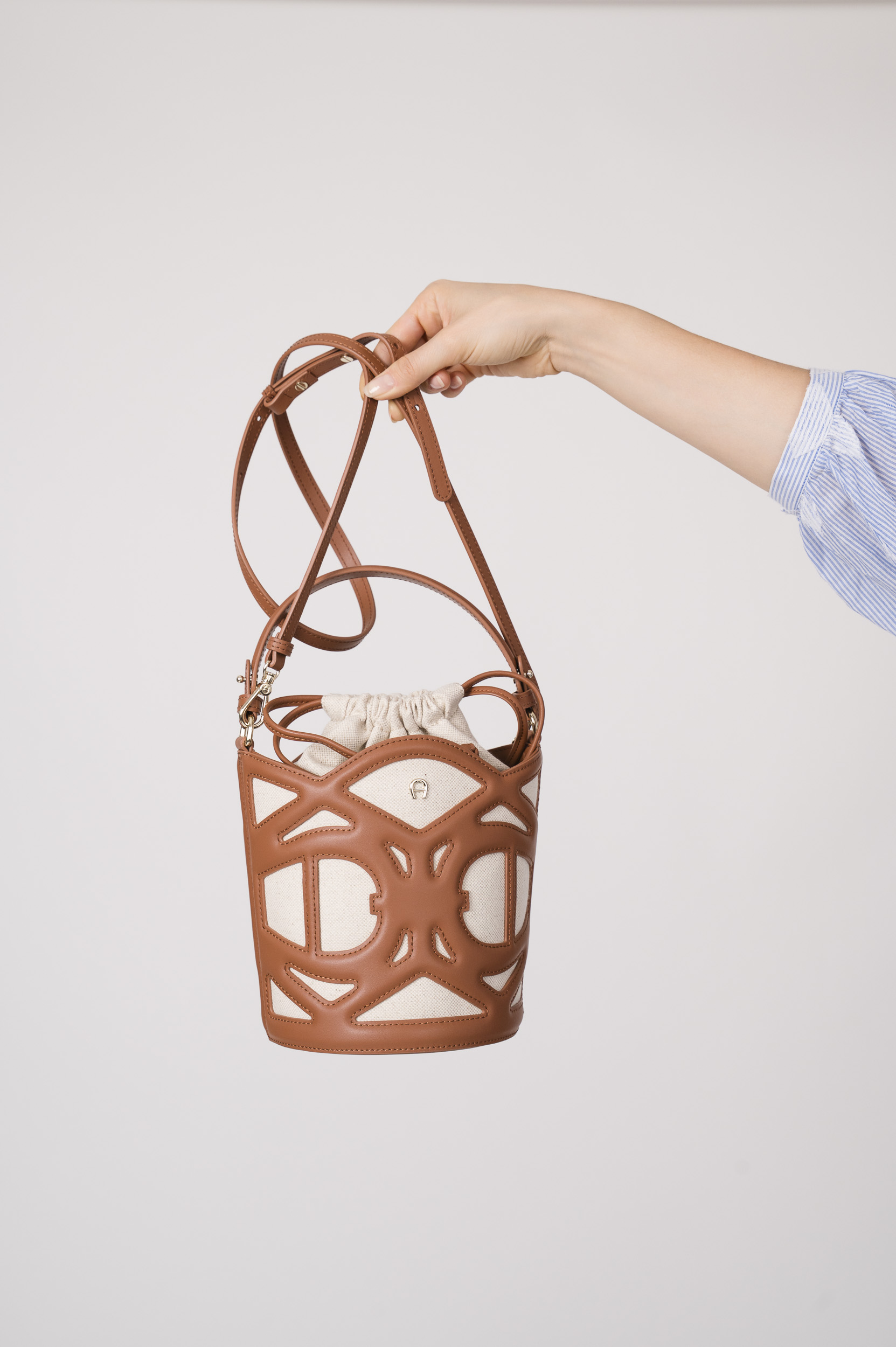 Model zeigt eine braun-beige Tasche der Marke Aigner.