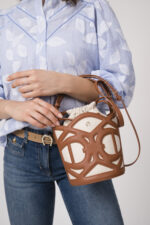 Model trägt eine hellblau-weiß gemusterte Bluse der Marke 0039 Italy und eine blaue Jeans der Marke Luisa Cerano und einen beigen Gürtel der Marke Aigner sowie eine braun-beige Tasche der Marke Aigner.