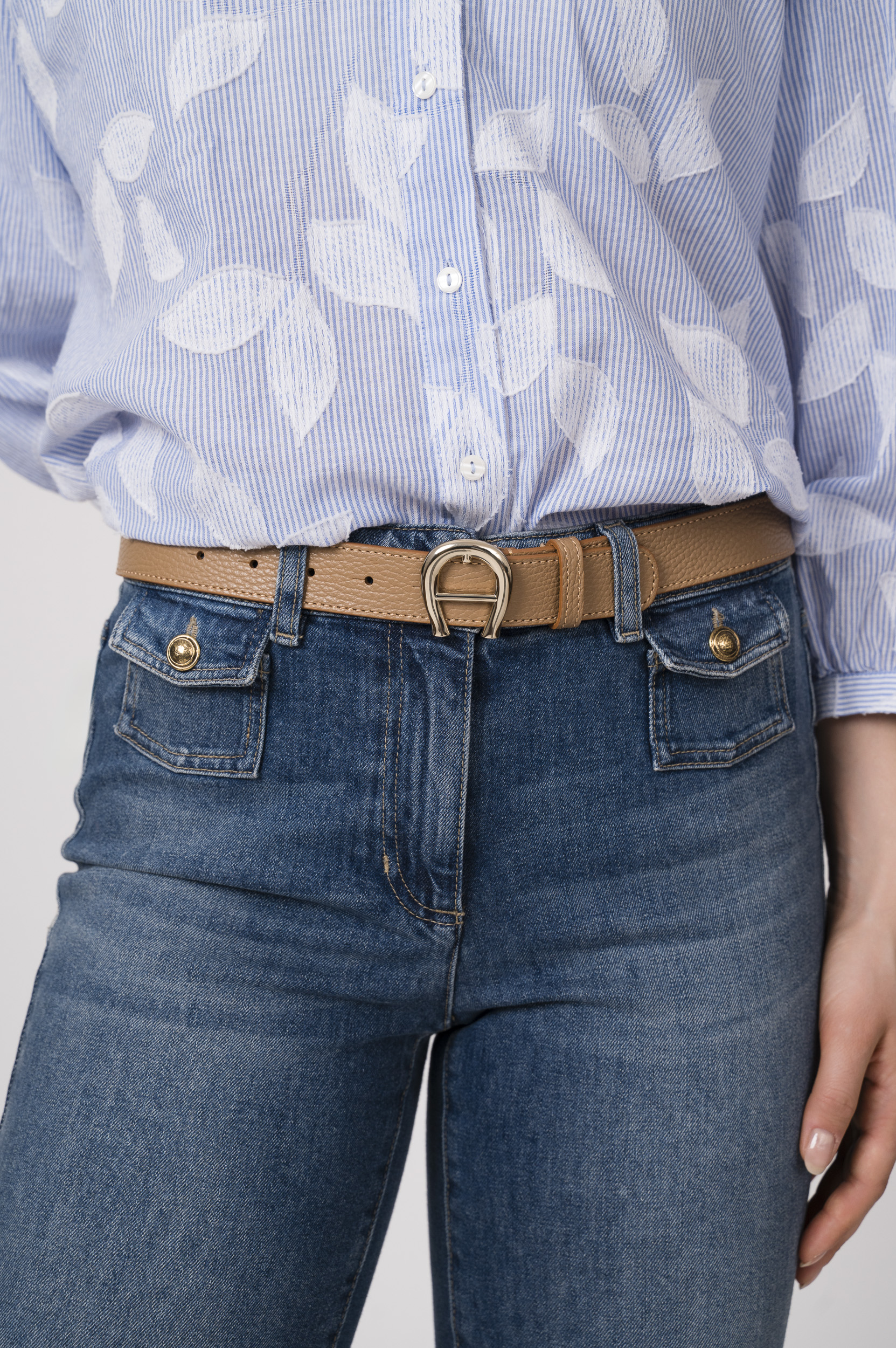 Model trägt eine blaue Jeans der Marke Luisa Cerano und einen beigen Gürtel der Marke Aigner.