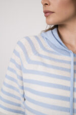 Model trägt einen hellblau-weiß gestreiften Pullover der Marke Allude.