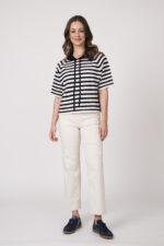 Model trägt einen dunkelblau-weiß gestreiften Pullover der Marke Allude und eine sand-farbige Hose der Marke Cambio sowie dunkelblaue Sneaker der Marke Caval.