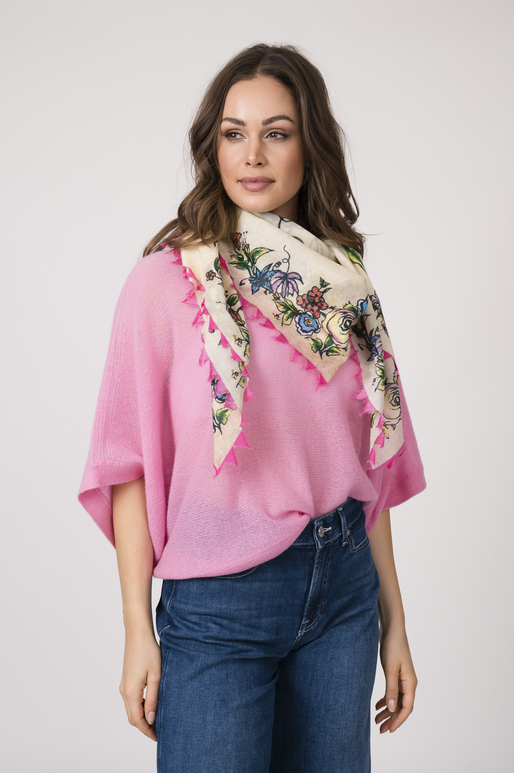 Model trägt einen feinen Cashmere-Kurzarmpullover der Marke Absolut Cashmere in Rosa, dazu einen passenden Schal der Marke Faliero Sarti und eine Jeans der Marke 7 for all mankind.