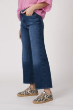 Model trägt einen feinen Cashmere-Kurzarmpullover der Marke Absolut Cashmere in Rosa, Jeans der Marke 7 for all mankind und Sneaker in Leo Optik der Marke Caval.