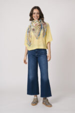 Model trägt einen feinen Cashmere-Kurzarmpullover der Marke Absolut Cashmere in Gelb, dazu einen passenden Schal der Marke Faliero Sarti, Sneaker der Marke Caval.