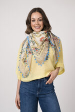 Model trägt einen feinen Cashmere-Kurzarmpullover der Marke Absolut Cashmere in Gelb, dazu einen passenden Schal der Marke Faliero Sarti.