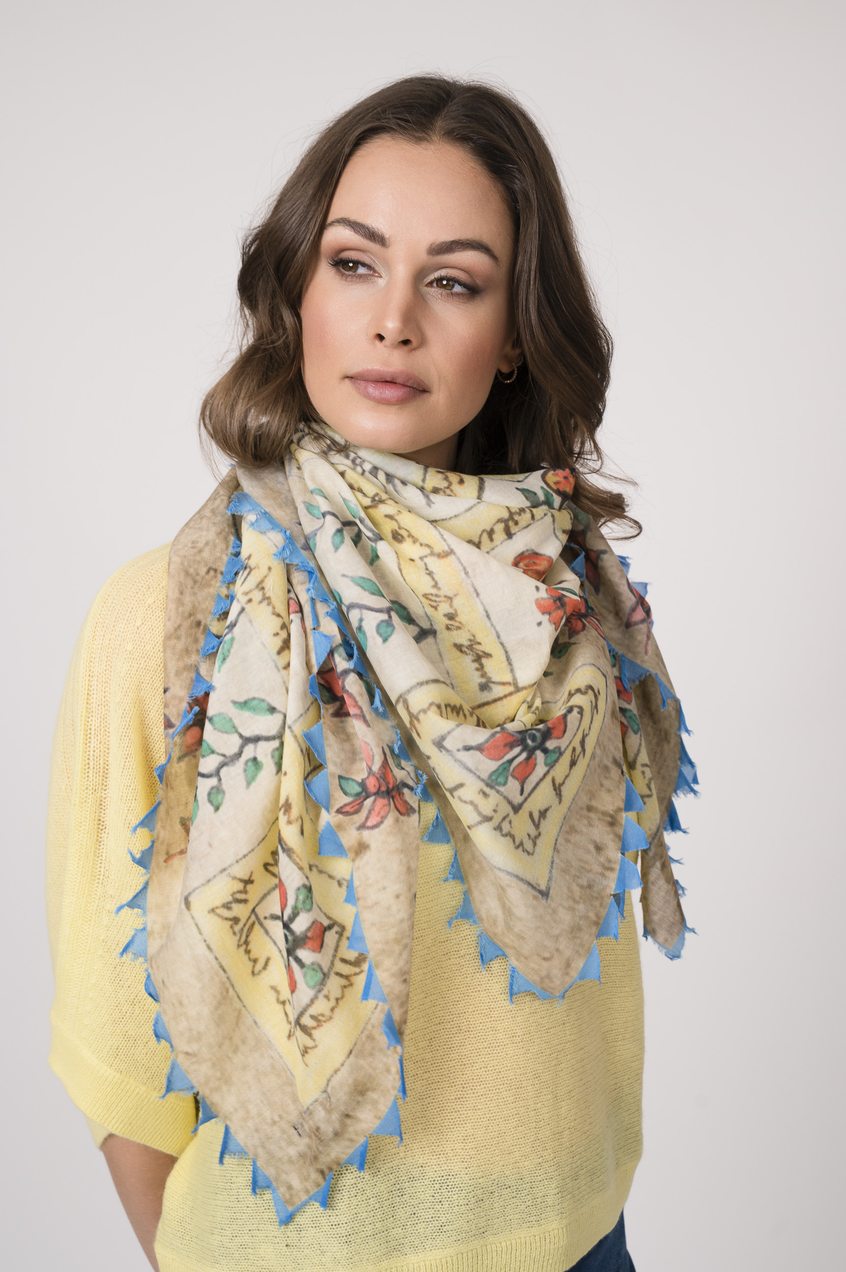 Model trägt einen feinen Cashmere-Kurzarmpullover der Marke Absolut Cashmere in Gelb, dazu einen passenden Schal der Marke Faliero Sarti.