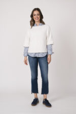 Model trägt einen weißen Kurzarmpullover der Marke Allude, die Bluse mit Blumenmuster ist von der Marke Rossana Diva. Die Jeans sind von True Religion, die passenden Sneaker sind von Caval.