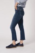 Model trägt eine Bluse mit Blumenmuster der Marke Rossana Diva, eine Jeans der Marke True Religion und blaue Sneaker der Marke Caval