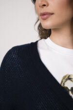 Model trägt eine marine-blaue Strickweste der Marke Hemisphere, ein weißes Shirt mit Zeichnung einer Frau der Marke Unartig