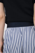 Model trägt einen marine-blauen Kurzarmpullover der Marke Allude und einen blau weiß gestreiften Rock der Marke JOOP.