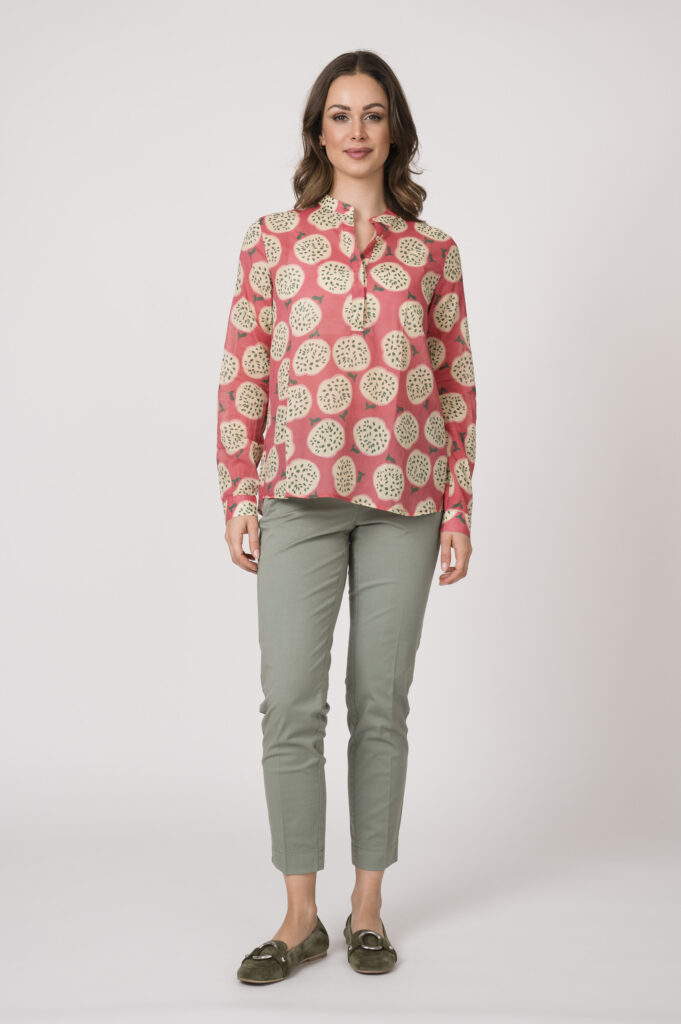 Model trägt eine pink gemusterte Bluse der Marke 0039 Italy und eine hellgrüne Stoffhose der Mark Cambio.