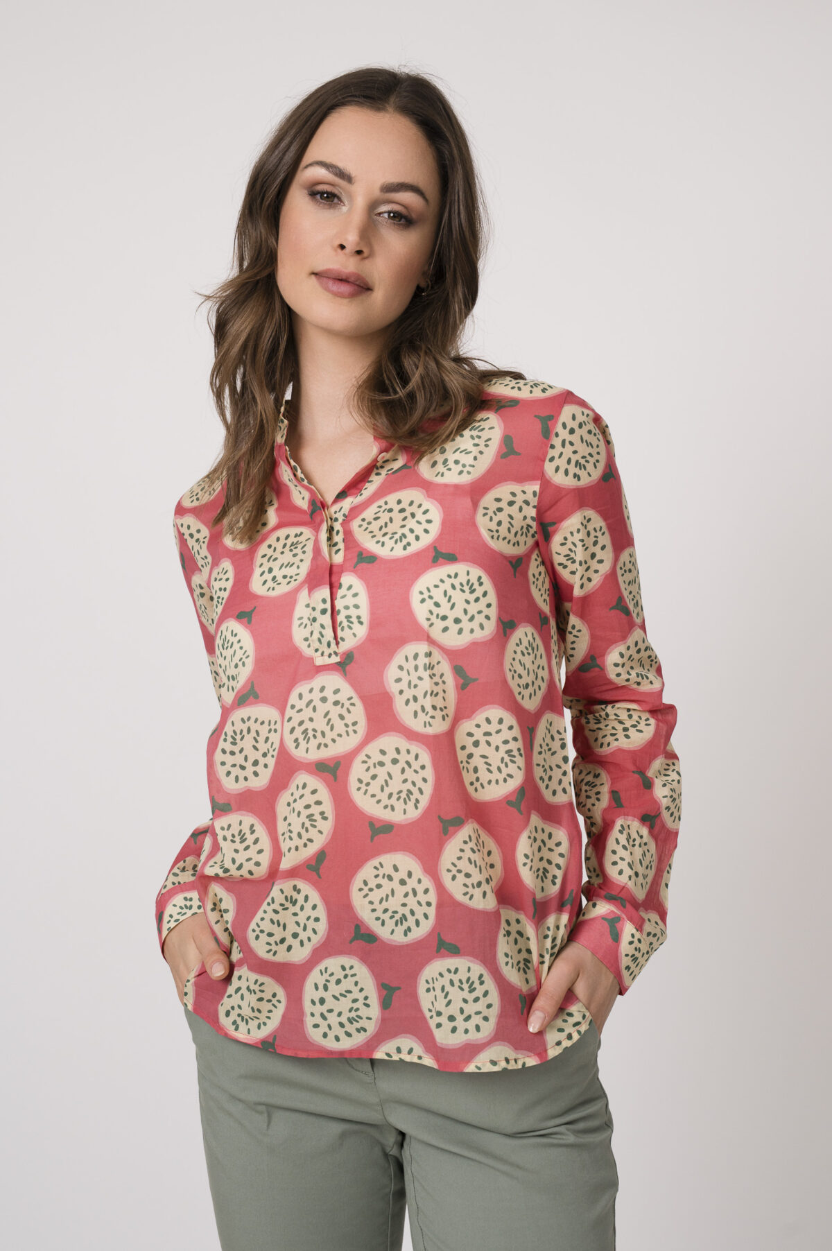 Model trägt eine pink gemusterte Bluse der Marke 0039 Italy und eine hellgrüne Stoffhose der Mark Cambio.