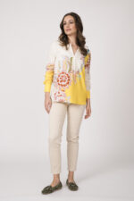 Model trägt eine beige-gelbe Bluse der Marke Herzens und eine sand-farbige Stoffhose der Marke Mason’s.