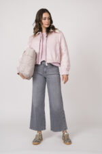 Model trägt eine rosa Daunen-Wendejacke der Marke Luisa Cerano, einen rosa Pullover der Marke Luisa Cerano, hellgraue Jeans der Marke 7 for all mankind und eine beige Tasche der Marke VEE Collective sowie Sneaker in Leoprint der Marke Voile Blanche.