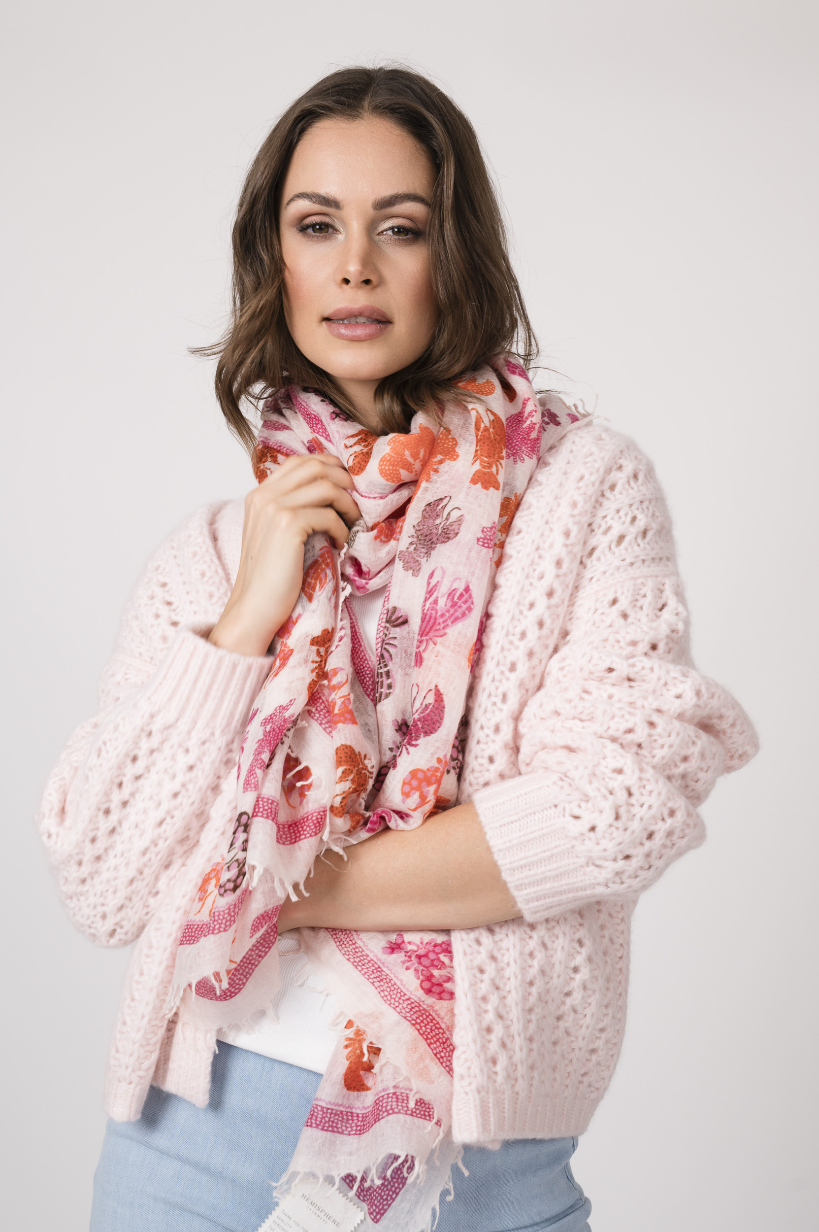 Model trägt einen Schal der Marke Hemisphere und eine rosé Strickweste der Marke Hemisphere, ein weißes Top der Marke Luisa Cerano und eine hellblaue Jeans der Marke Closed.