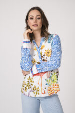 Model trägt eine bunte Bluse der Marke Herzens und eine hellblaue Jeans der Marke Closed.