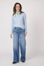 Das Model präsentiert ein Tuch mit dem ikonischen Muster von Faliero Sarti, kombiniert mit einem hellblauen Langarmpullover von Allude und einer Jeans von Cambio.