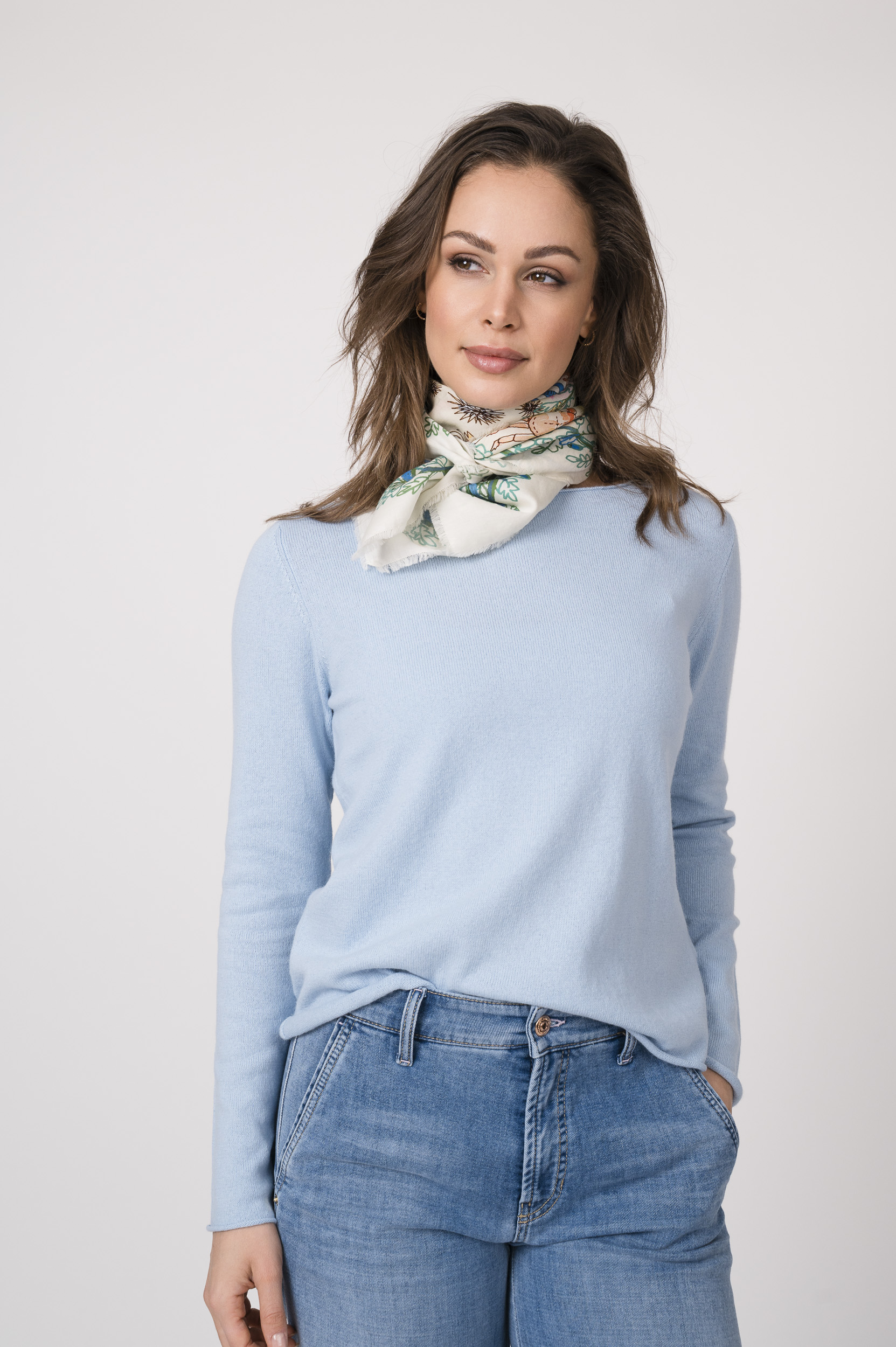 Das Model präsentiert ein Tuch mit dem ikonischen Muster von Faliero Sarti, kombiniert mit einem hellblauen Langarmpullover von Allude und einer Jeans von Cambio.