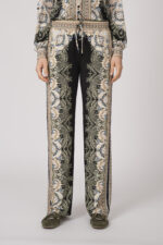 Model trägt eine fließend gemusterte Hose in schwarz und beige der Marke Hale Bob.