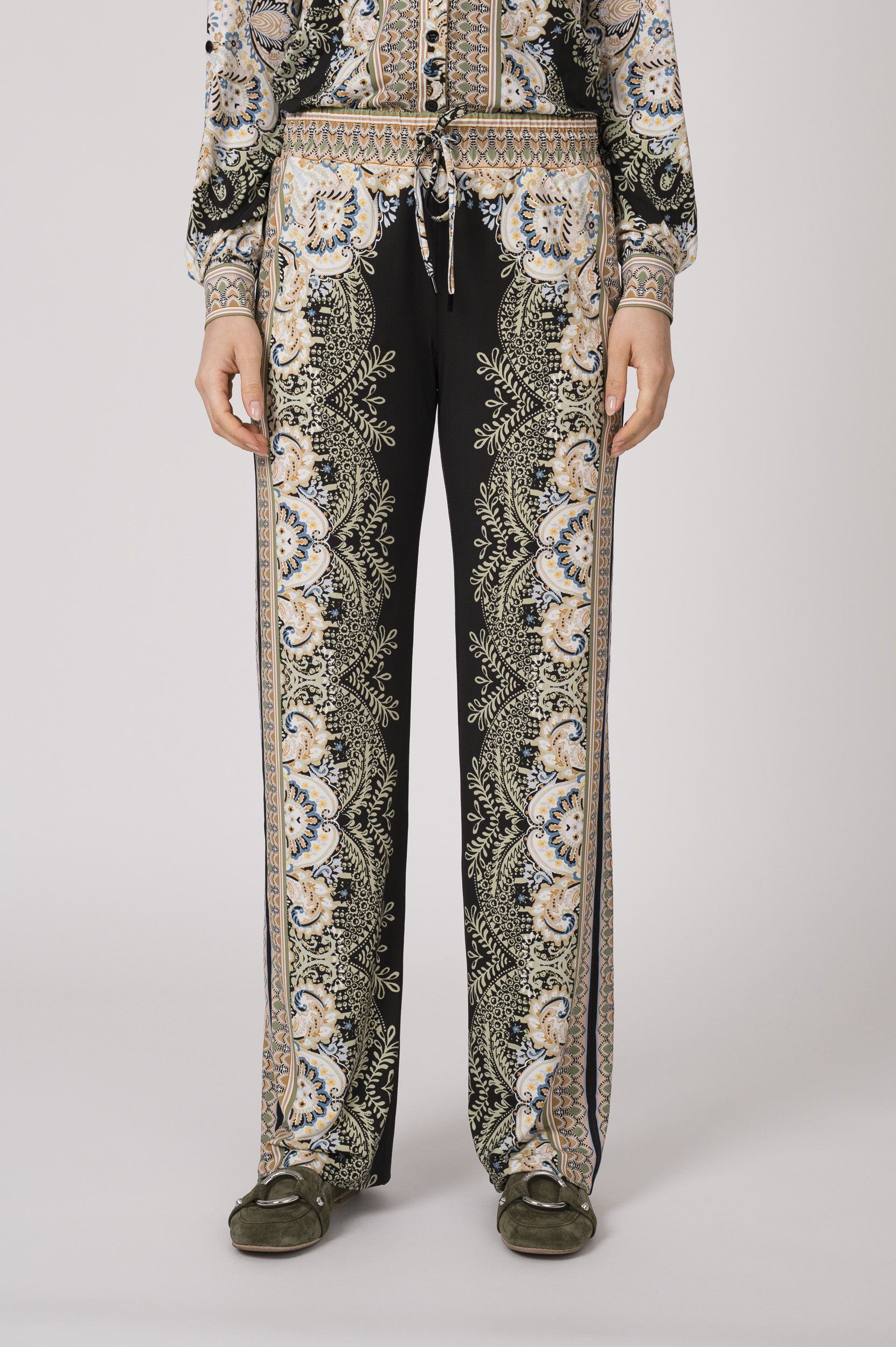 Model trägt eine fließend gemusterte Hose in schwarz und beige der Marke Hale Bob.