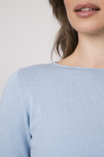 Model trägt einen hellblauen Pullover der Marke Allude